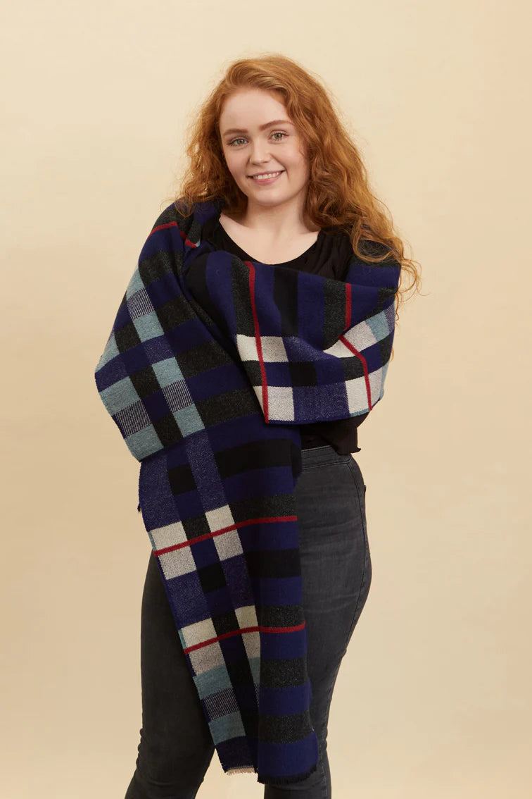Woman wearing a large plaid scarf against a beige background