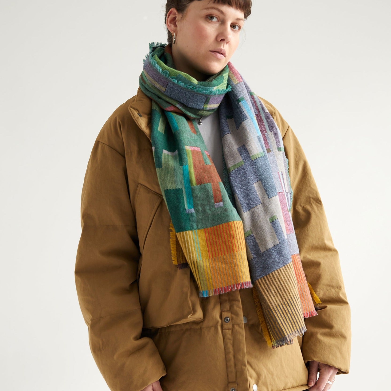 Multicolored geometric patterned wool scarf with frayed edges.