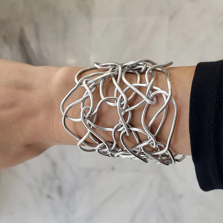 Silver bracelet on a wrist against a neutral background