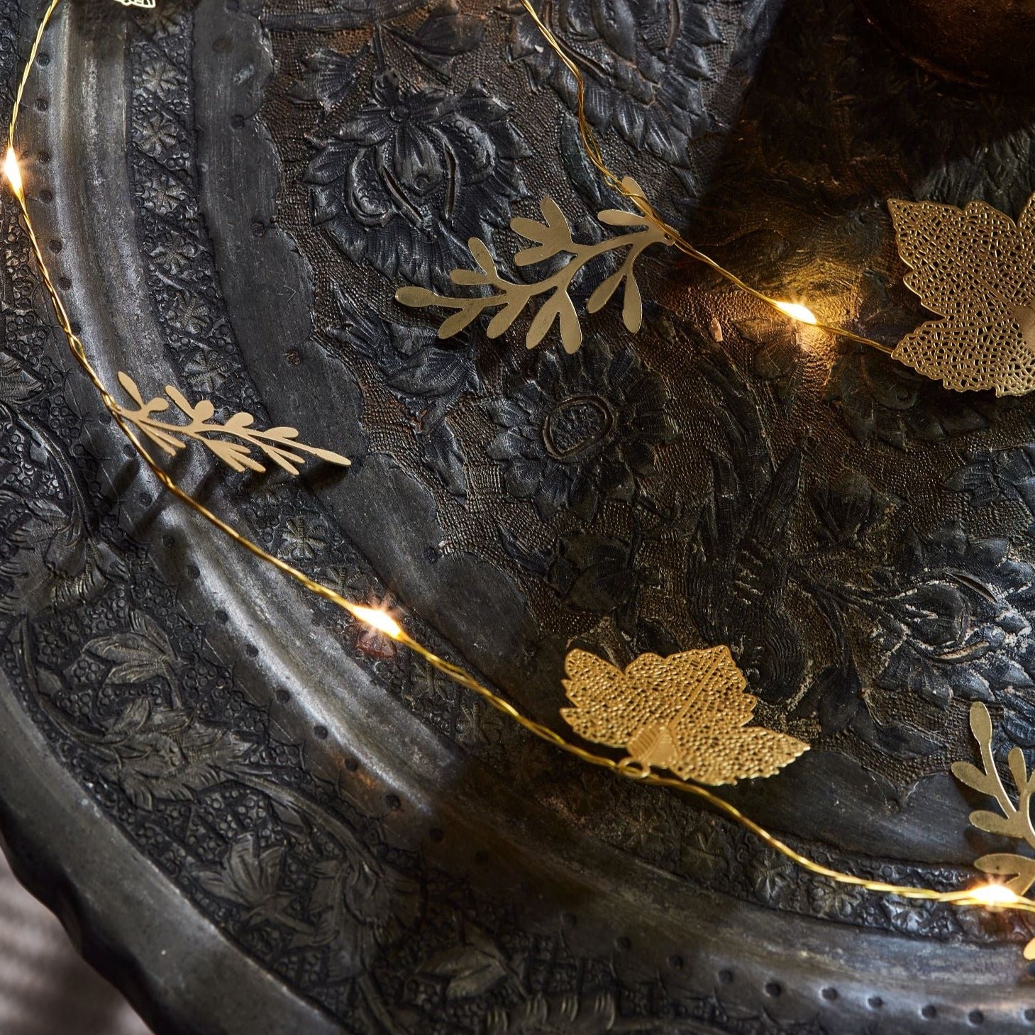 Gold leaf-shaped fairy lights strung on a thin copper wire.