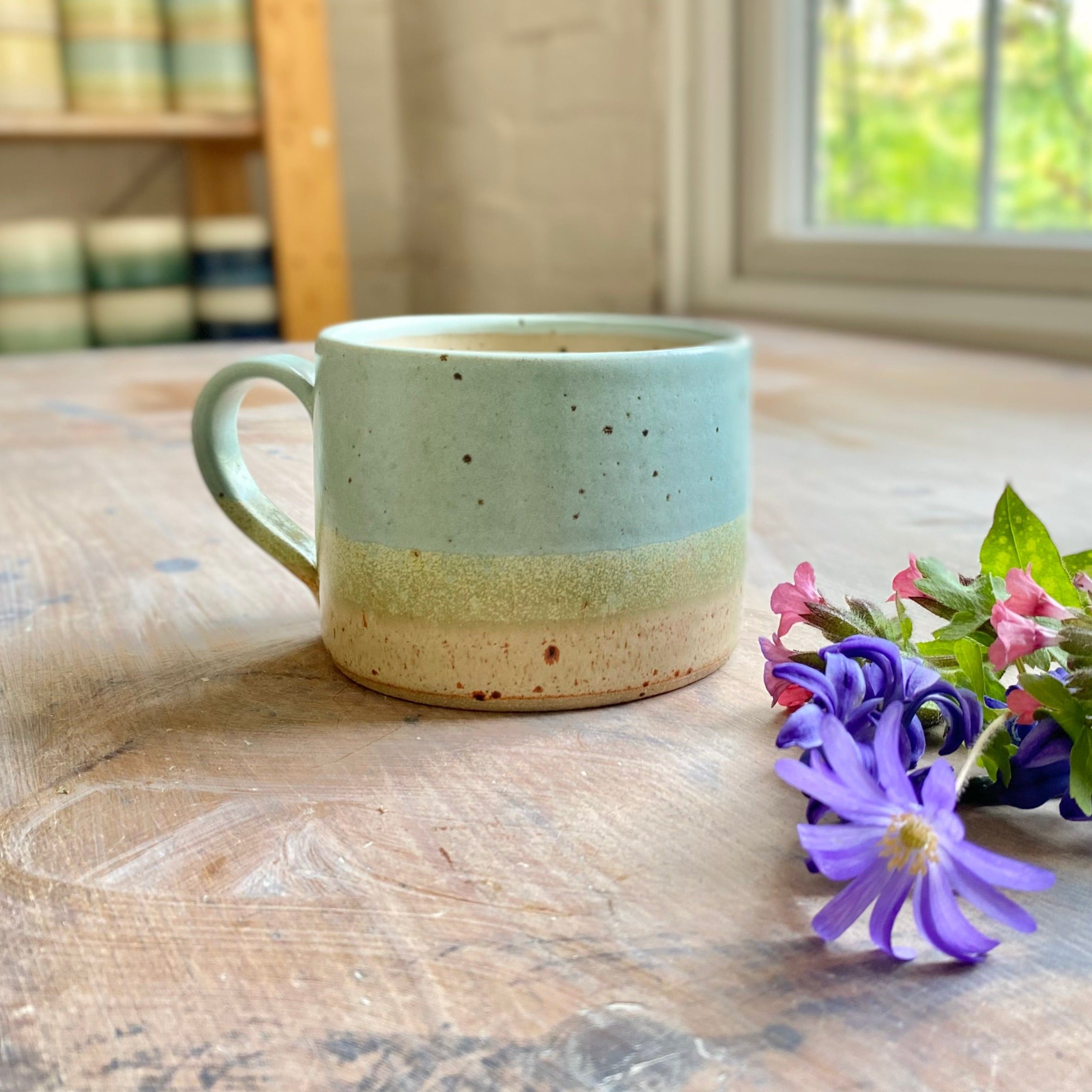 Hand-thrown stoneware mug with speckled light blue, green, and beige glaze.