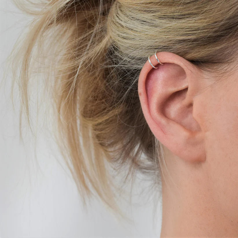 Silver double ear cuffs worn on the upper cartilage of an ear.
