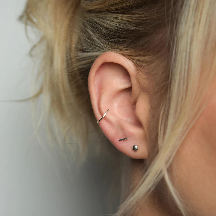 Silver hoop and stud earrings.  The hoop is in the upper ear cartilage, and the studs are in the lower lobe.