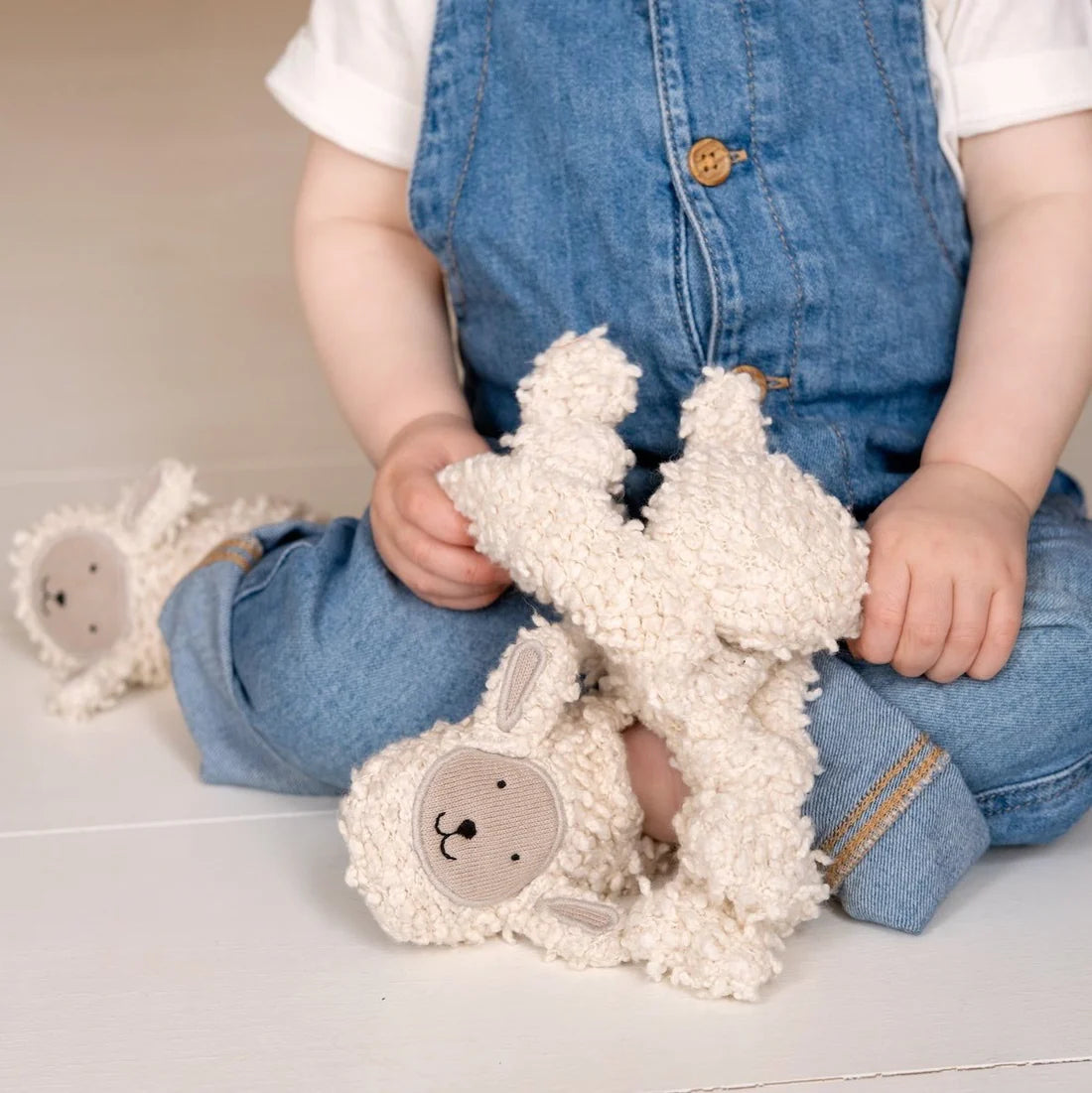 Child holding a plush toy with a neutral background