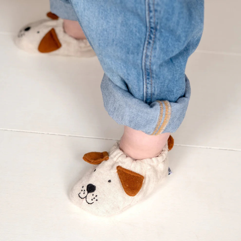 Off-white baby booties with brown felt dog face appliqués.