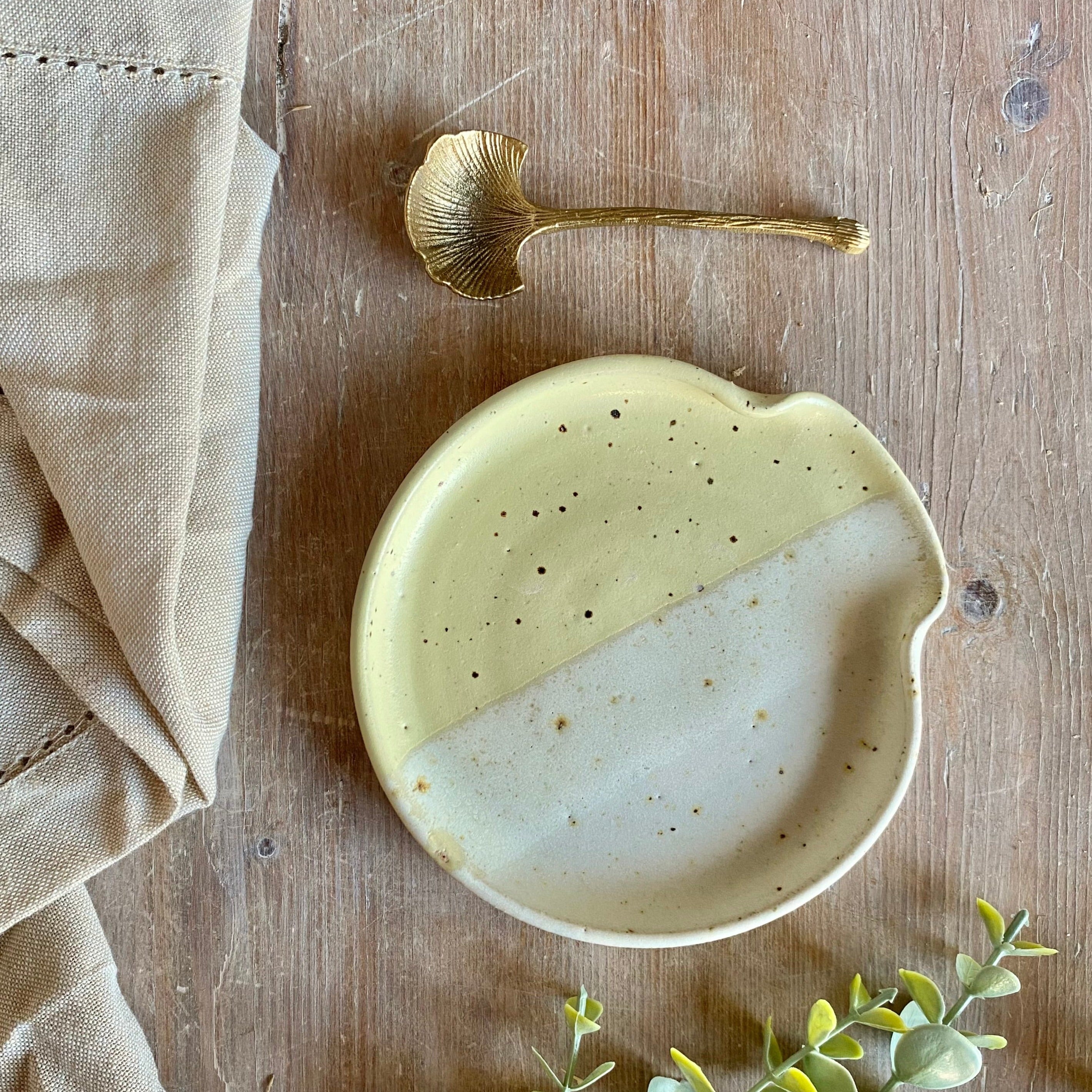 Hand-thrown ceramic dish with a speckled, two-tone glaze in pale yellow and off-white.