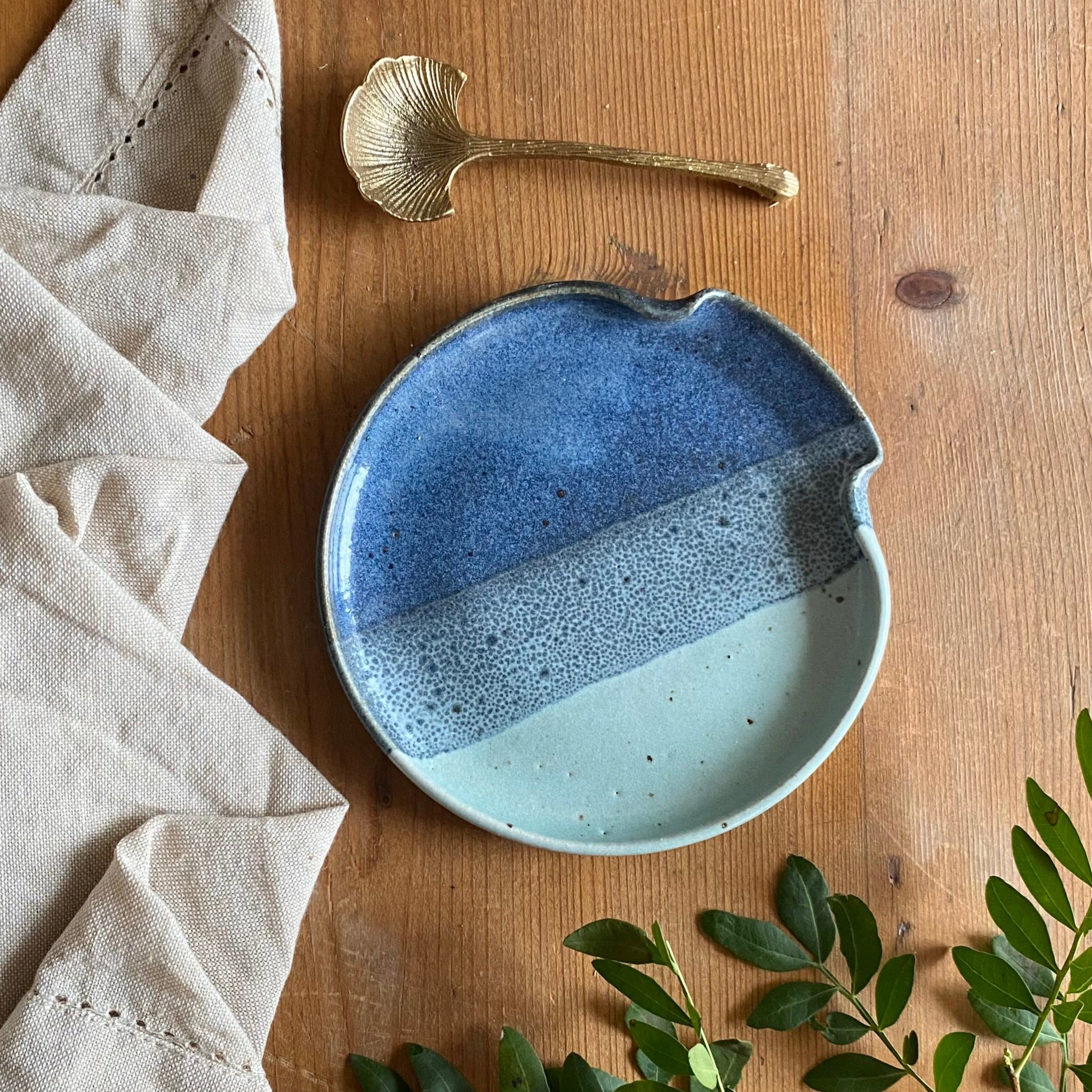 Handcrafted ceramic spoon rest with a blue and light blue speckled glaze.