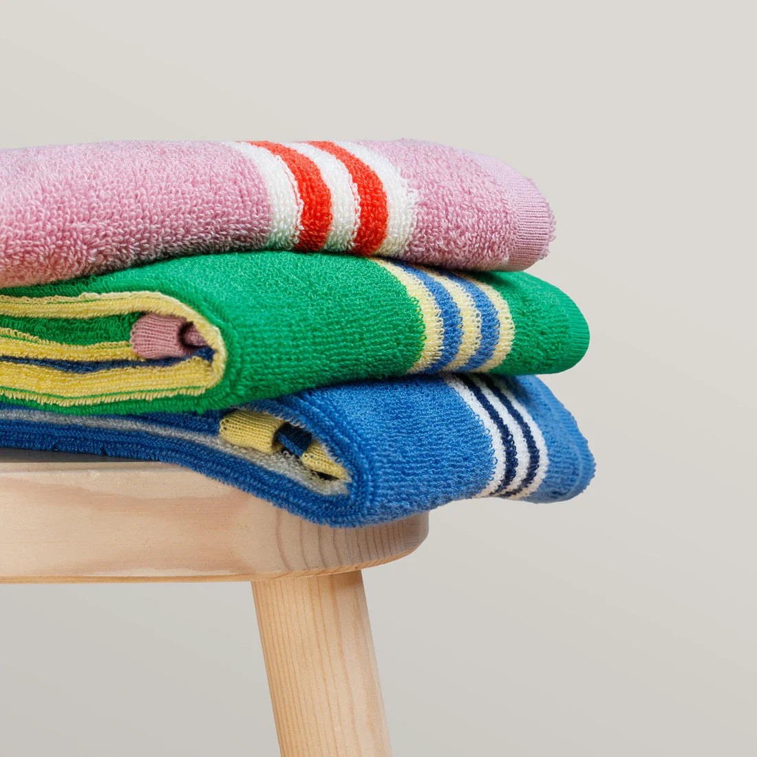 Stack of colorful socks on a wooden stool against a light background