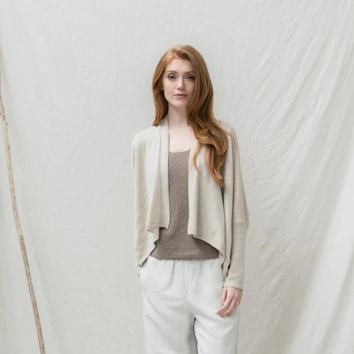 Beige linen cardigan with asymmetrical hem and long sleeves.