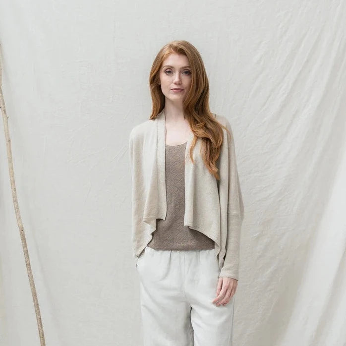 Lightweight, asymmetrical beige linen cardigan with long sleeves.