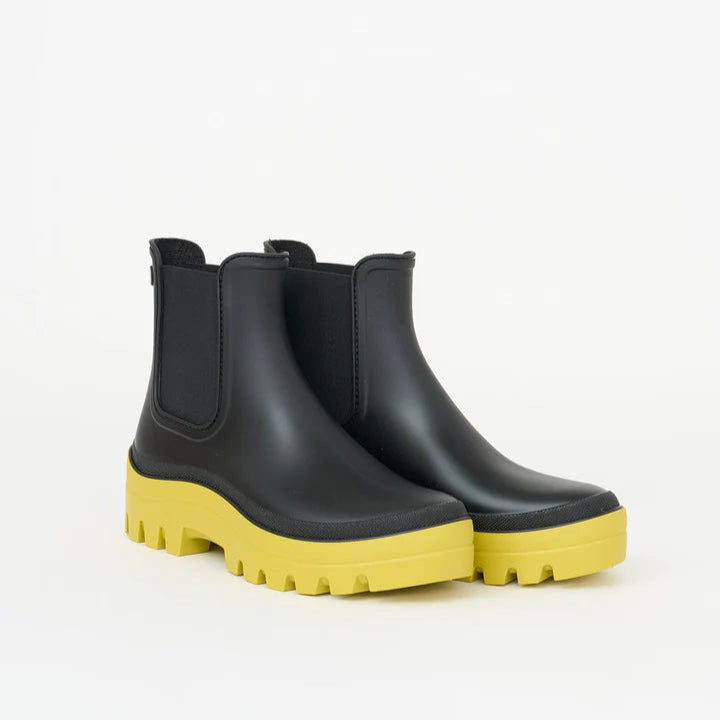Black rain boots with yellow soles on a white background