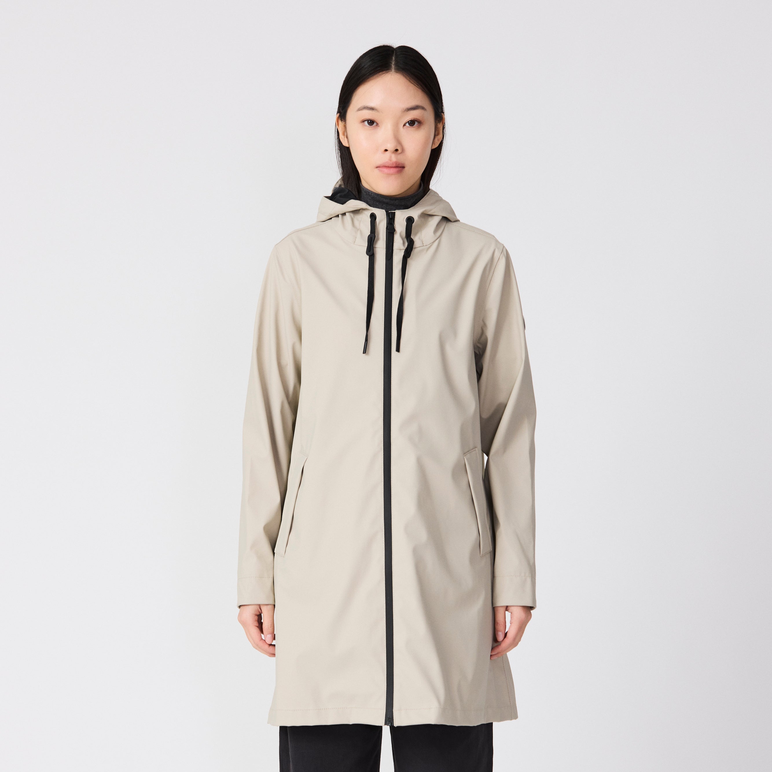 Person wearing a beige raincoat with a white background