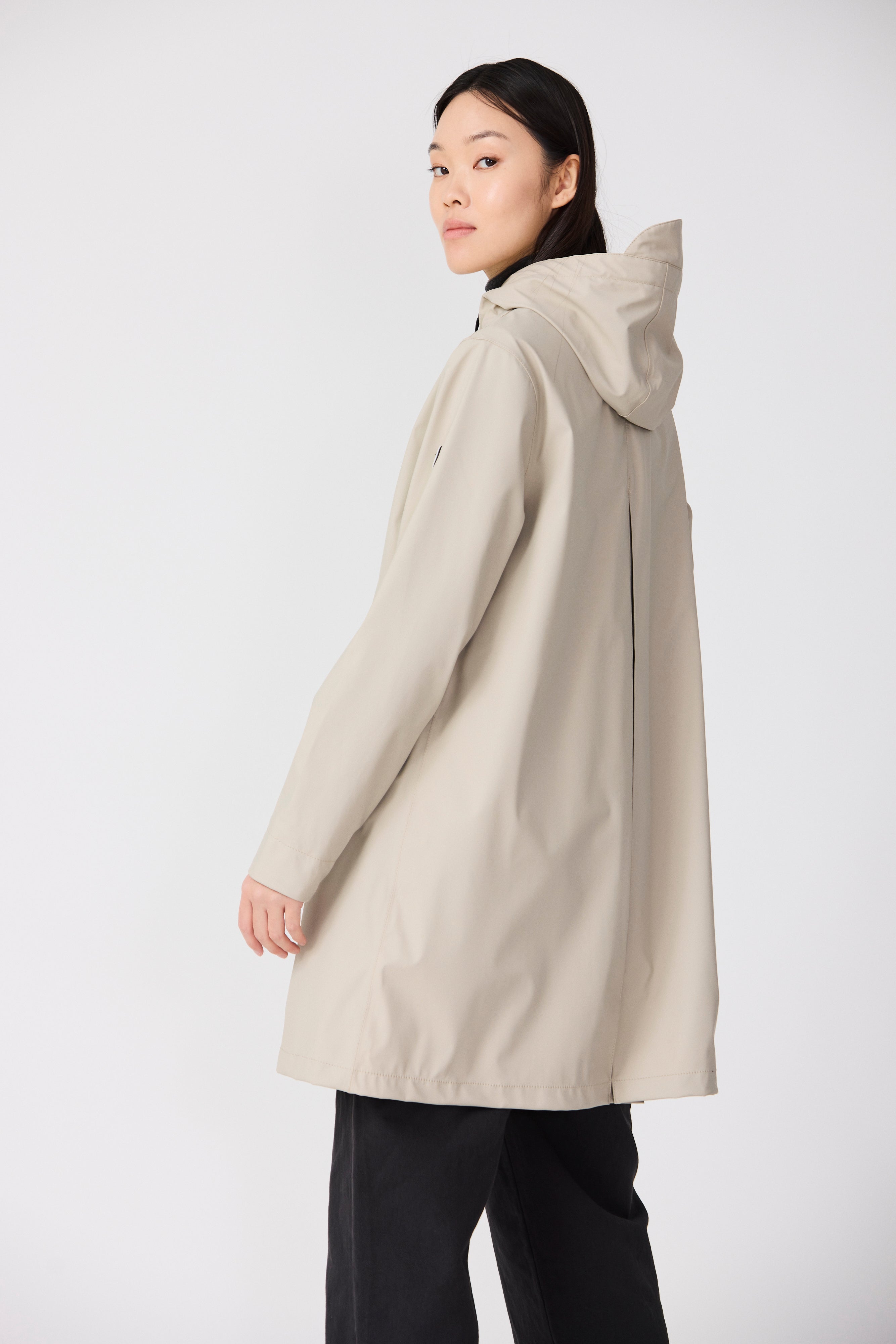 Woman wearing a beige hooded coat on a white background