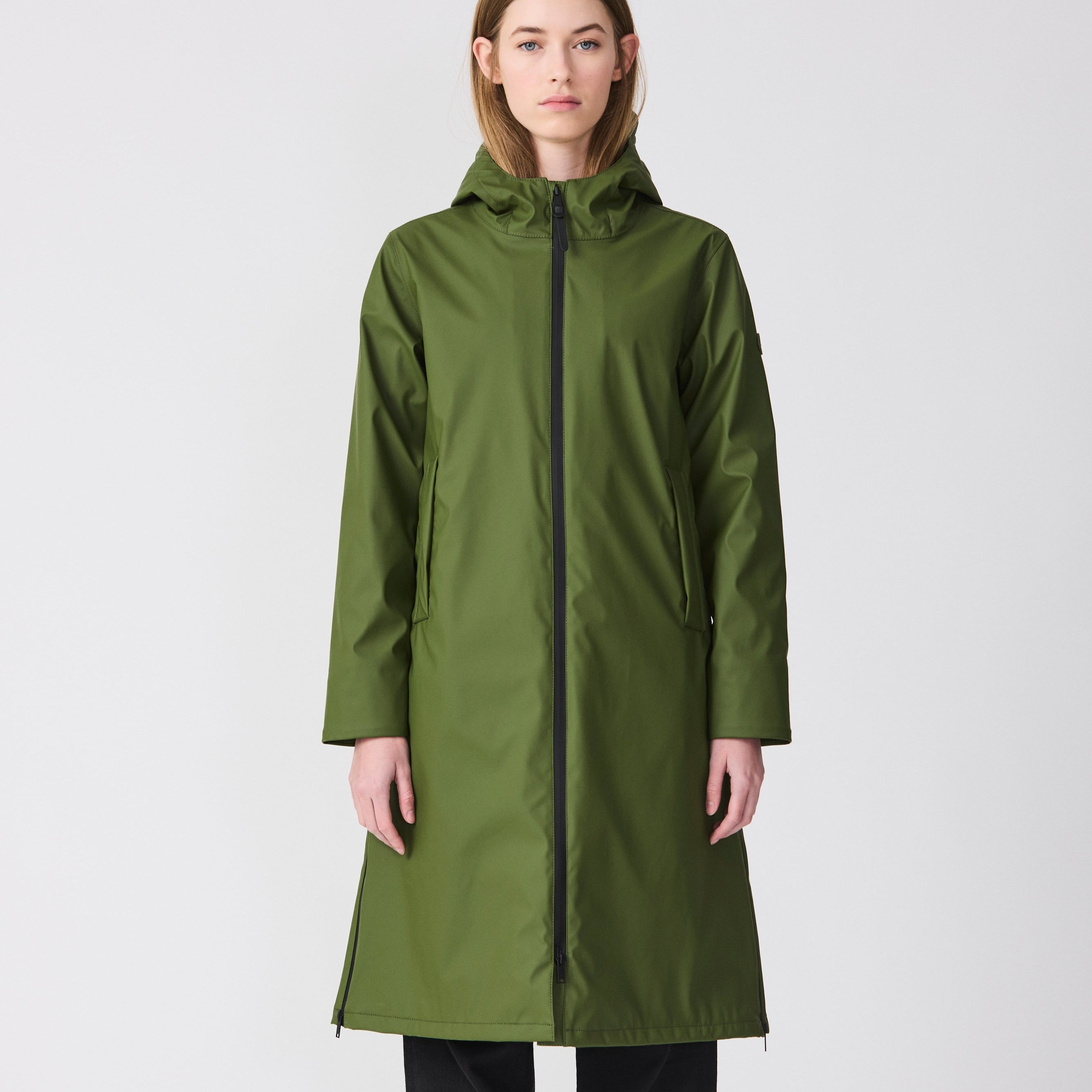 Woman wearing a green raincoat with a black zipper on a white background