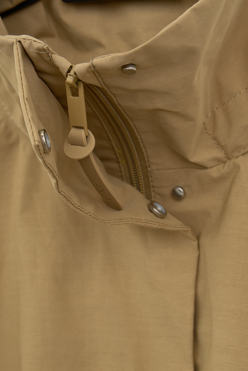 Close-up of a beige jacket with buttons and zippers