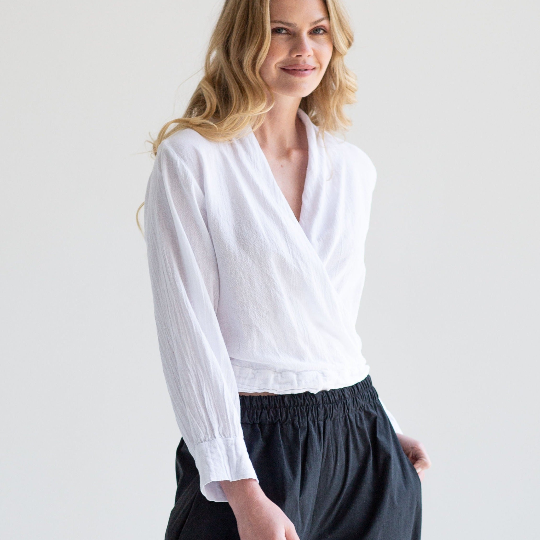 White long-sleeve wrap top with cuffed sleeves and a relaxed fit.