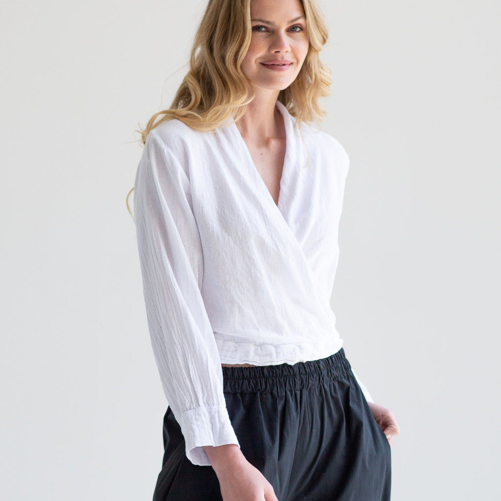 White long-sleeve wrap top with cuffed sleeves and a relaxed fit.