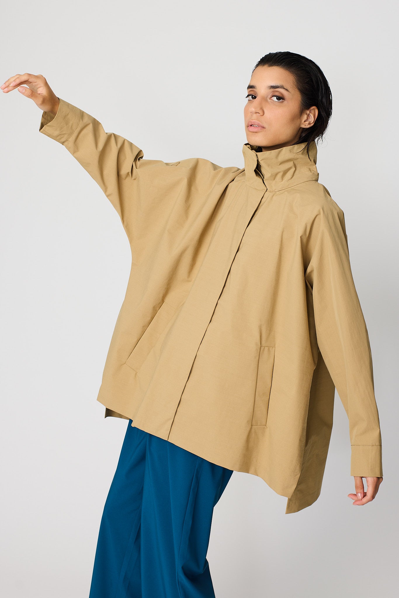 Person wearing a beige coat with a plain background