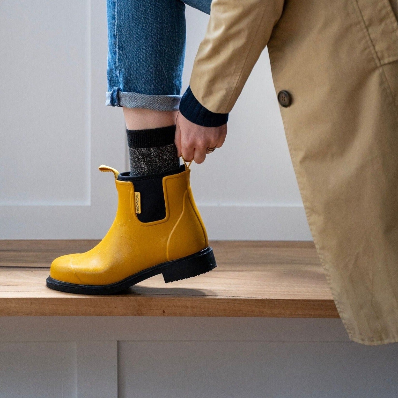 Mustard-yellow rubber ankle rain boot with a black sole and heel.  The boot has a small gold logo on the side.