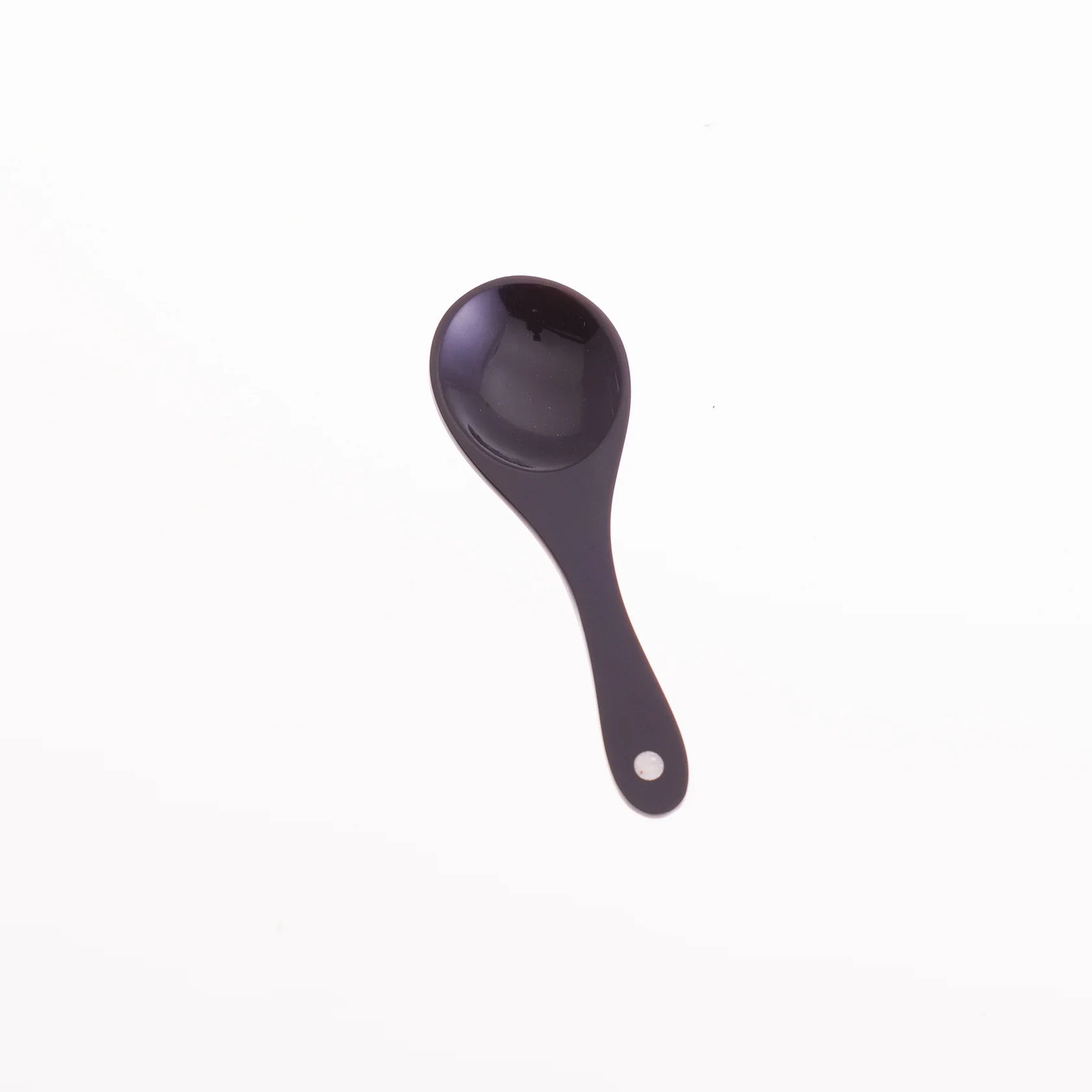 Dark-colored, rounded serving spoon with a small, light-colored circle at the end of its handle.