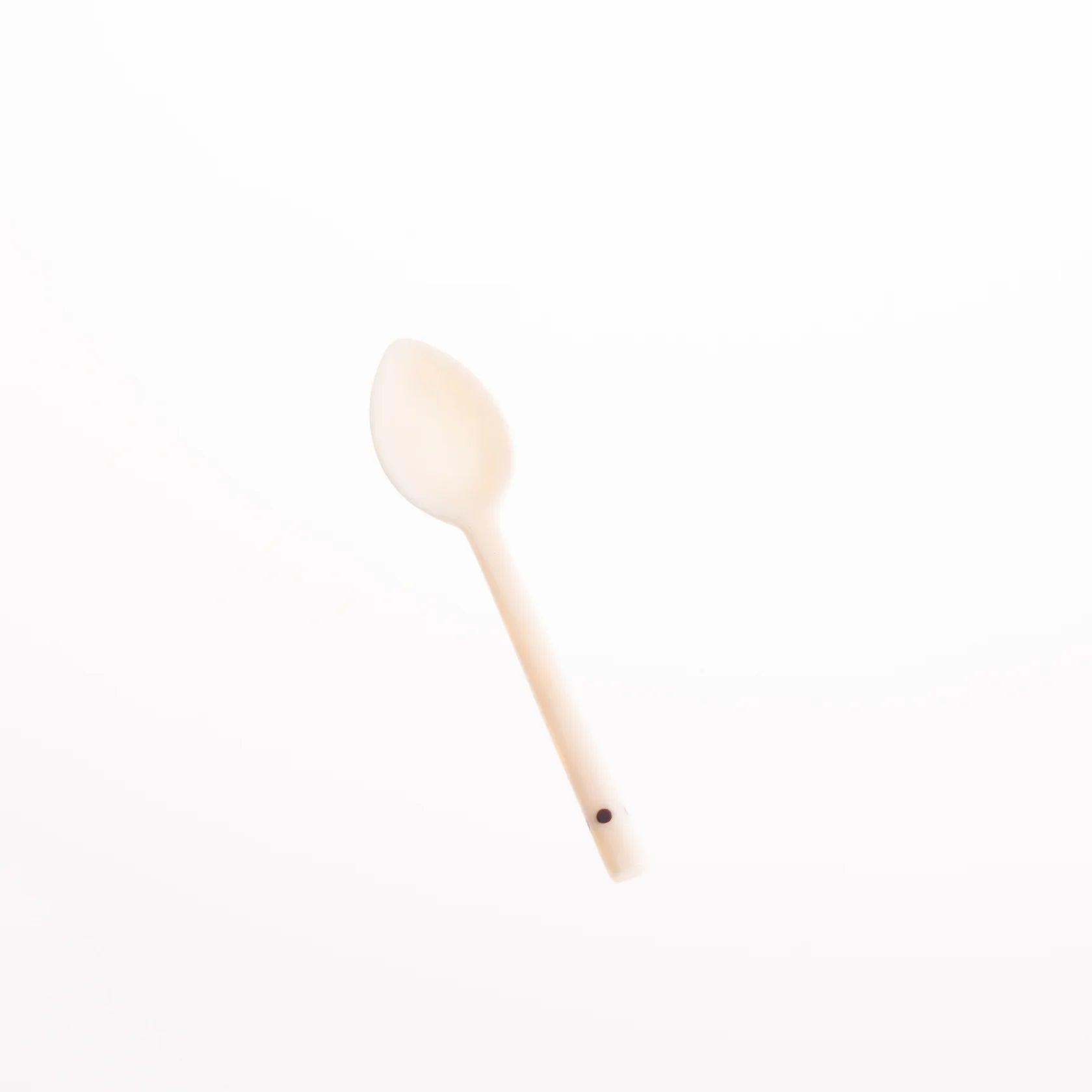Off-white, oval-shaped spoon with a long handle and a small dark dot near the end.