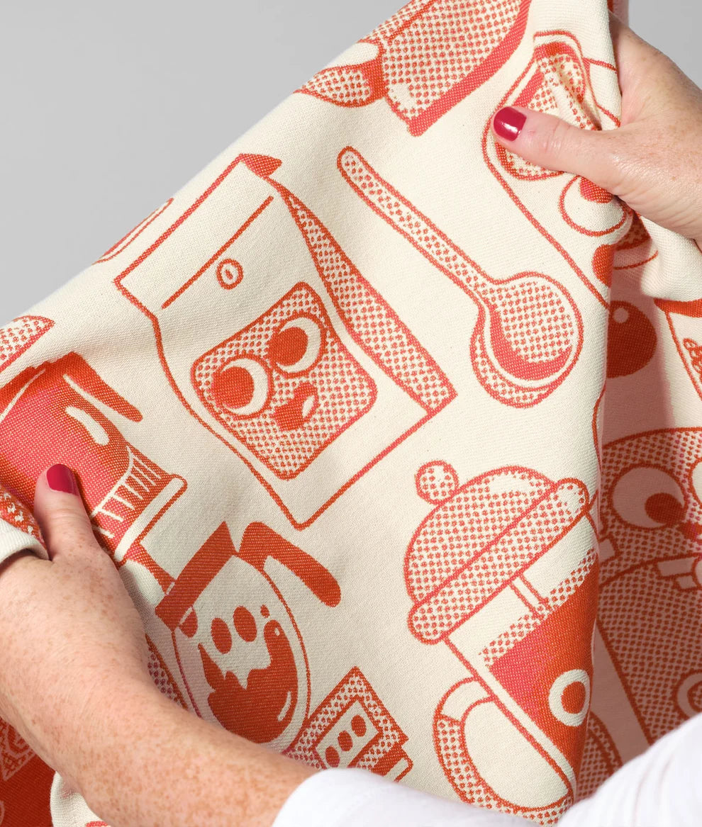 Person holding a fabric with red kitchen-themed patterns on a white background