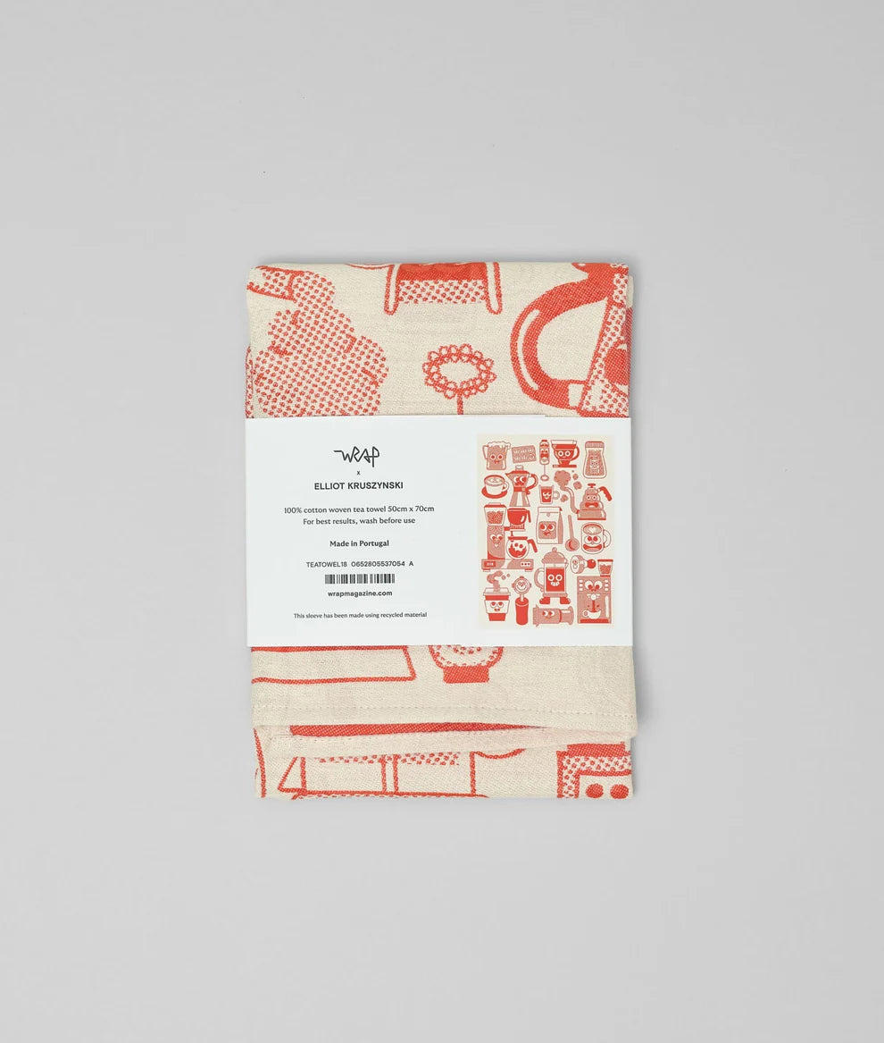 A folded tea towel with a red and cream kitchen-themed pattern, wrapped in a white paper band labeled 'Warp' and 'Ellie's Kitchenham'.