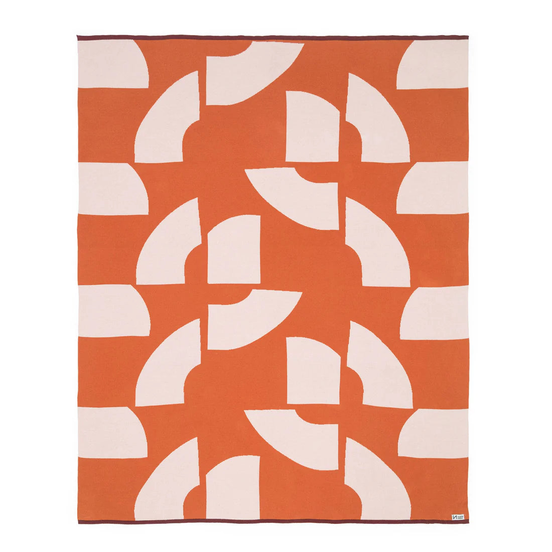 Geometric patterned rug with white shapes on an orange background
