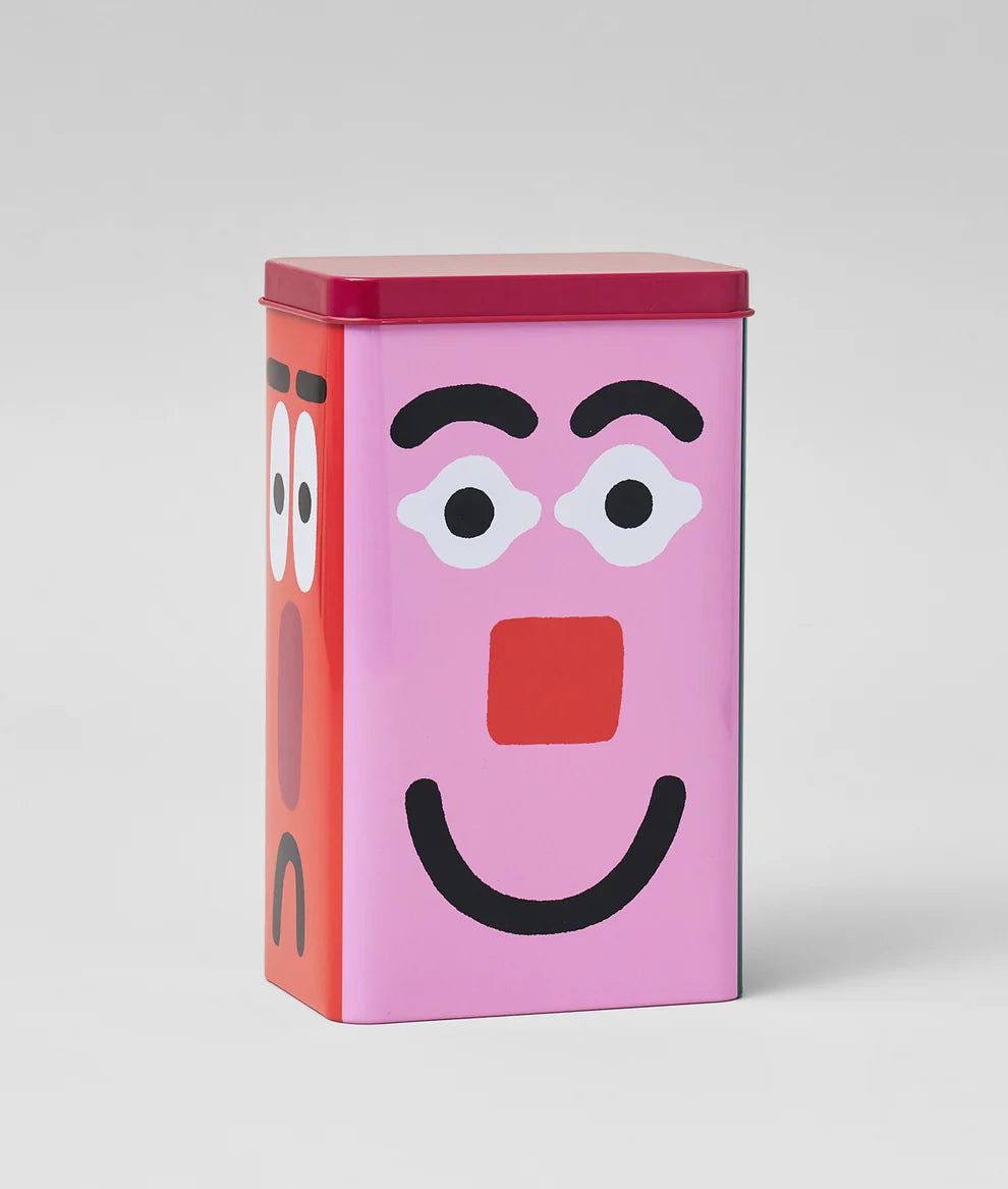 A rectangular metal tin with a pink front face and red side face, photographed on a clean light gray studio background.