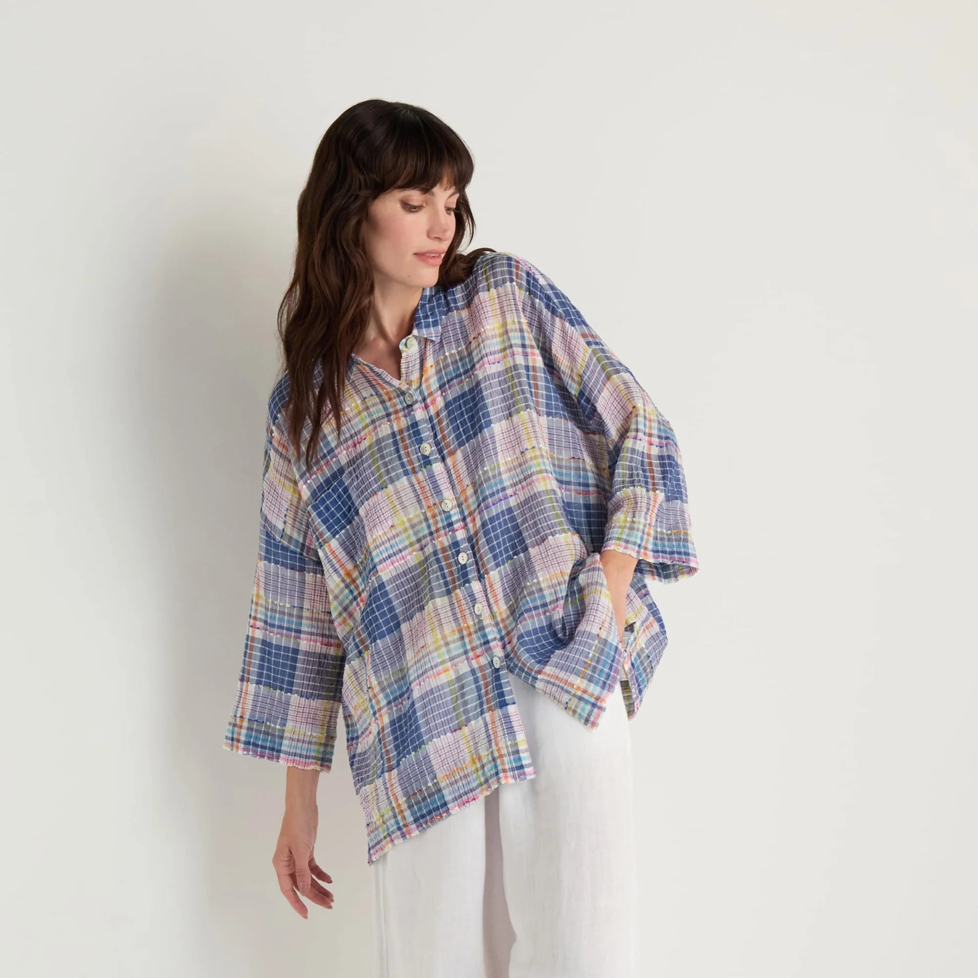 Woman wearing a plaid shirt over a white outfit on a white background