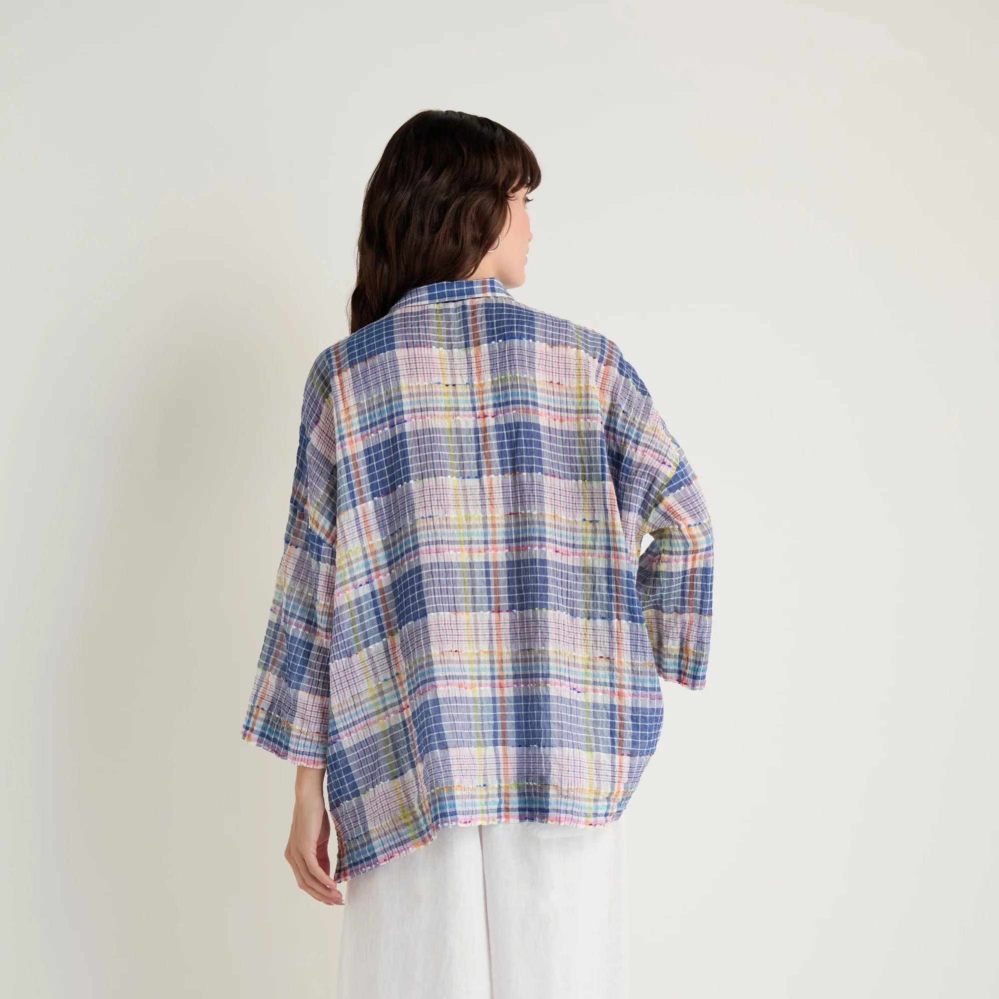 Person wearing a plaid shirt and white pants on a white background