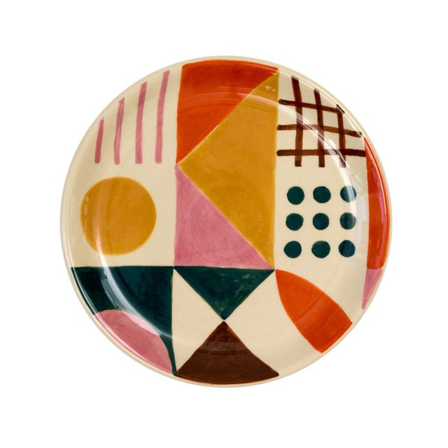 A round ceramic plate with a colorful mid-century modern geometric pattern, featuring pink stripes, a yellow circle, a pink triangle, and various other shapes on an off-white background, isolated on a white background.