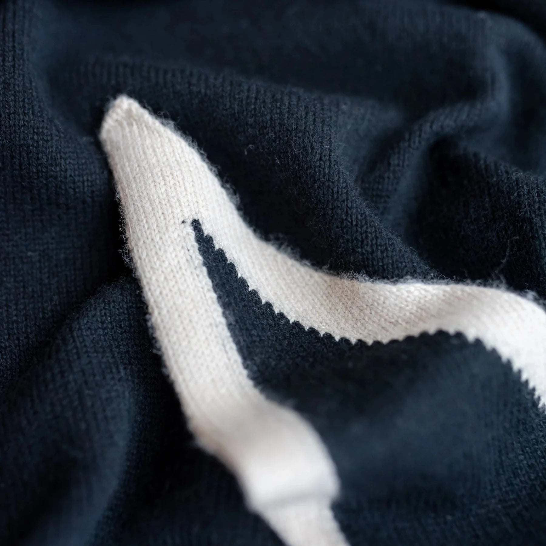 Close-up of a dark-navy and off-white knitted fabric with a textured surface.