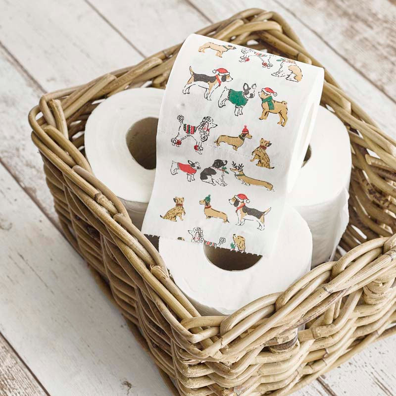 Roll of toilet paper with a dog-themed design in a woven basket on a wooden surface