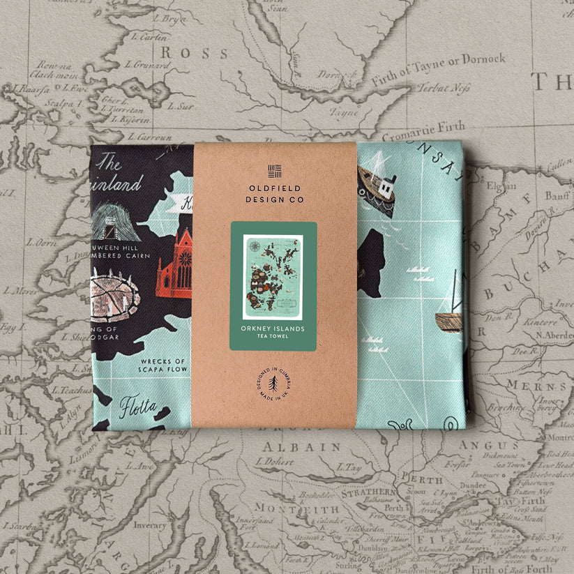 Orkney Islands tea towel; teal fabric with illustrated map and boat designs.  Packaged with a kraft paper label.