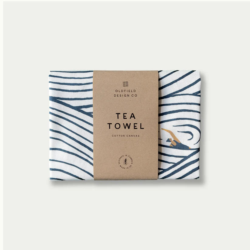 White cotton tea towel with navy blue wave design and a swimmer illustration;  Oldfield Design Co. branding.