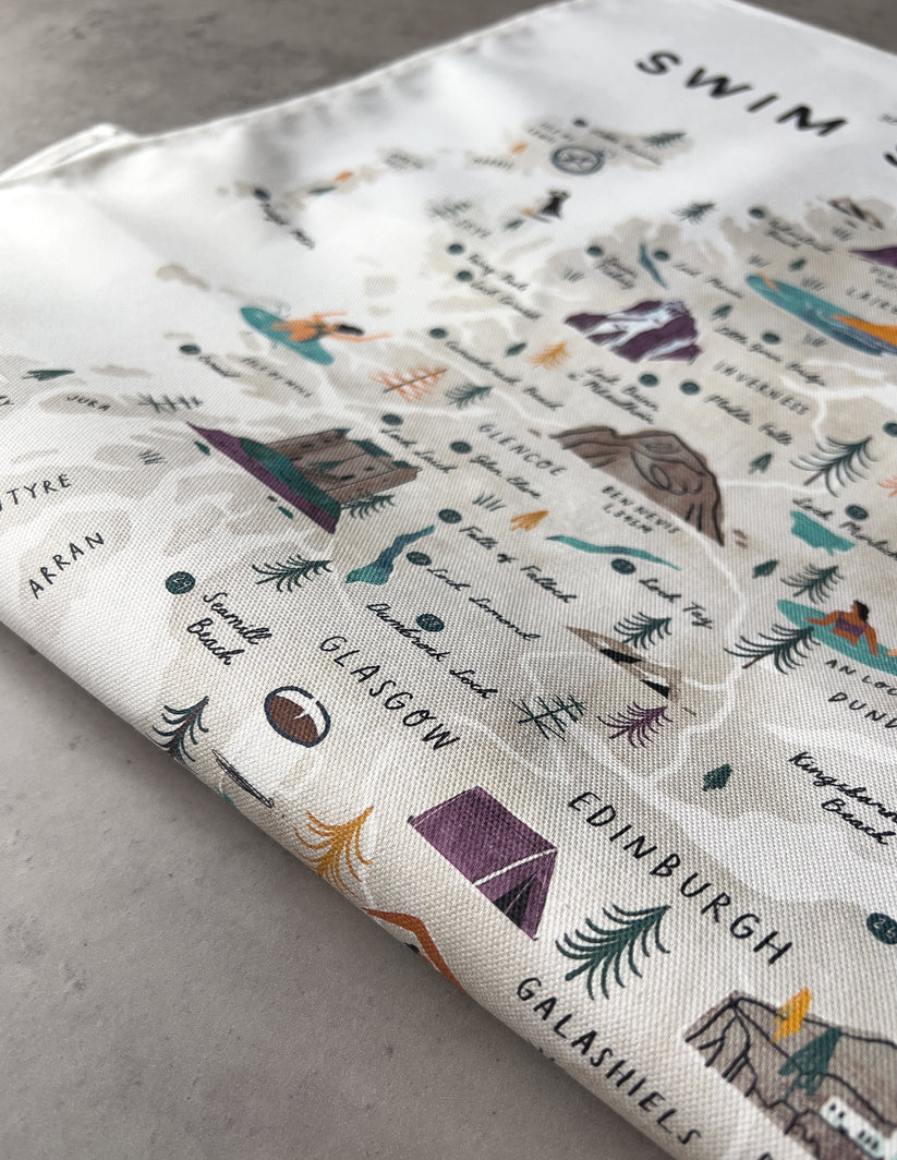 Off-white cotton tea towel featuring an illustrated map of Scotland's swimming locations, including city names and landmarks.
