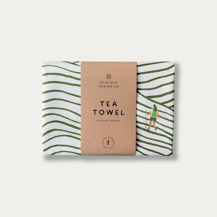 White cotton canvas tea towel with green wavy lines and a small hiker illustration.