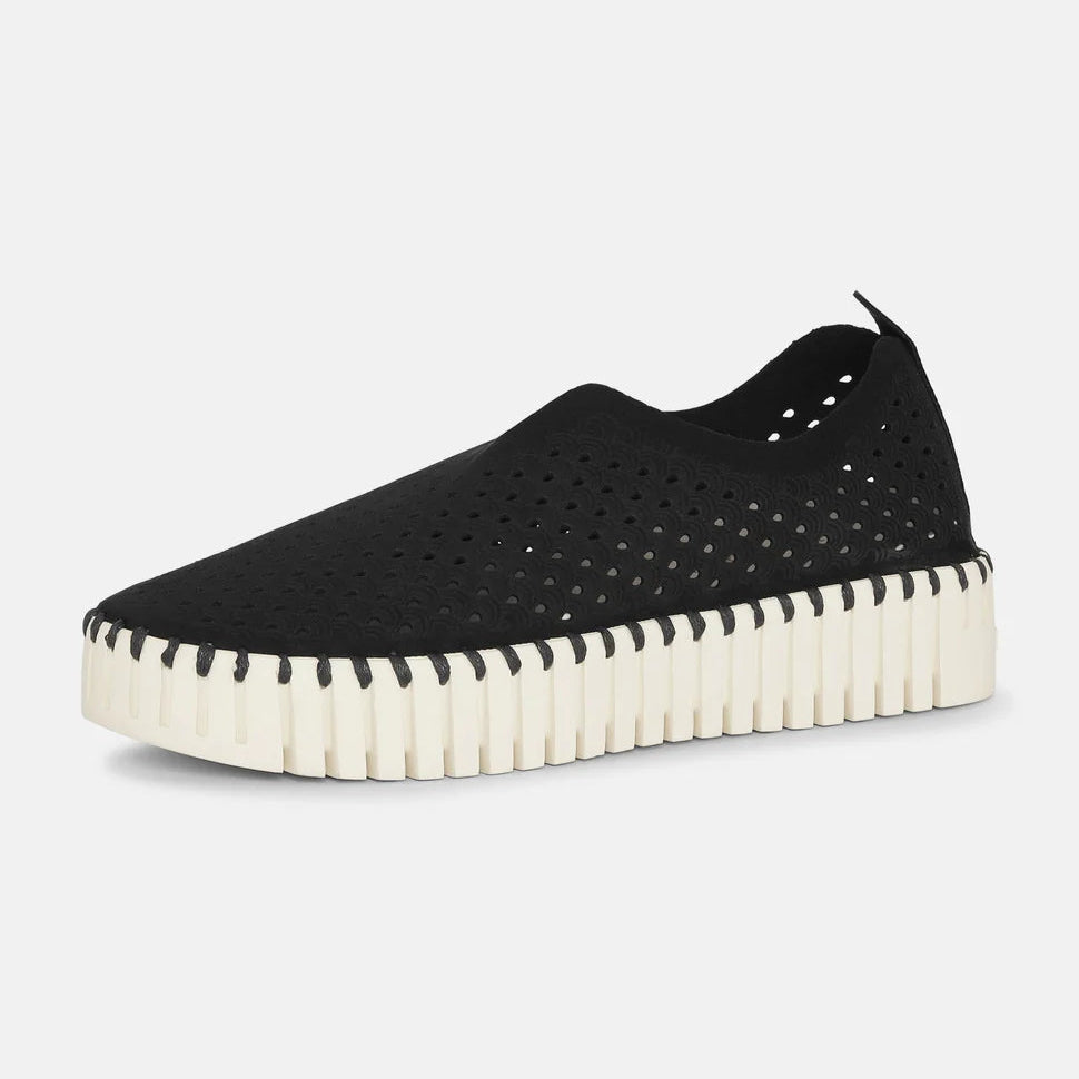 Black perforated slip-on sneaker with off-white scalloped sole. Lightweight, breathable design.