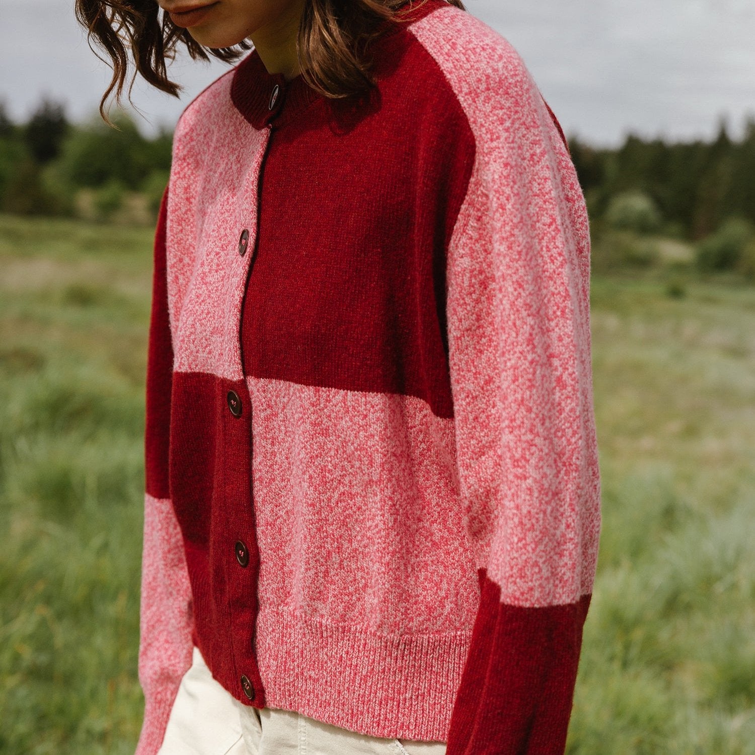 Red and pink color-blocked wool cardigan with button closure.
