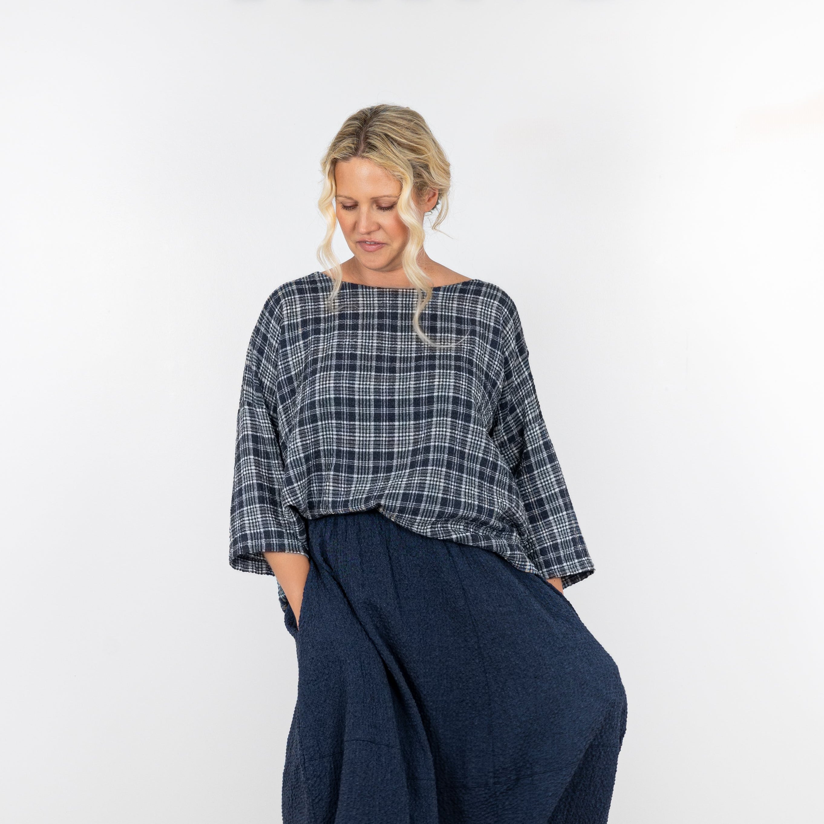 Woman wearing a plaid shirt and dark pants on a white background