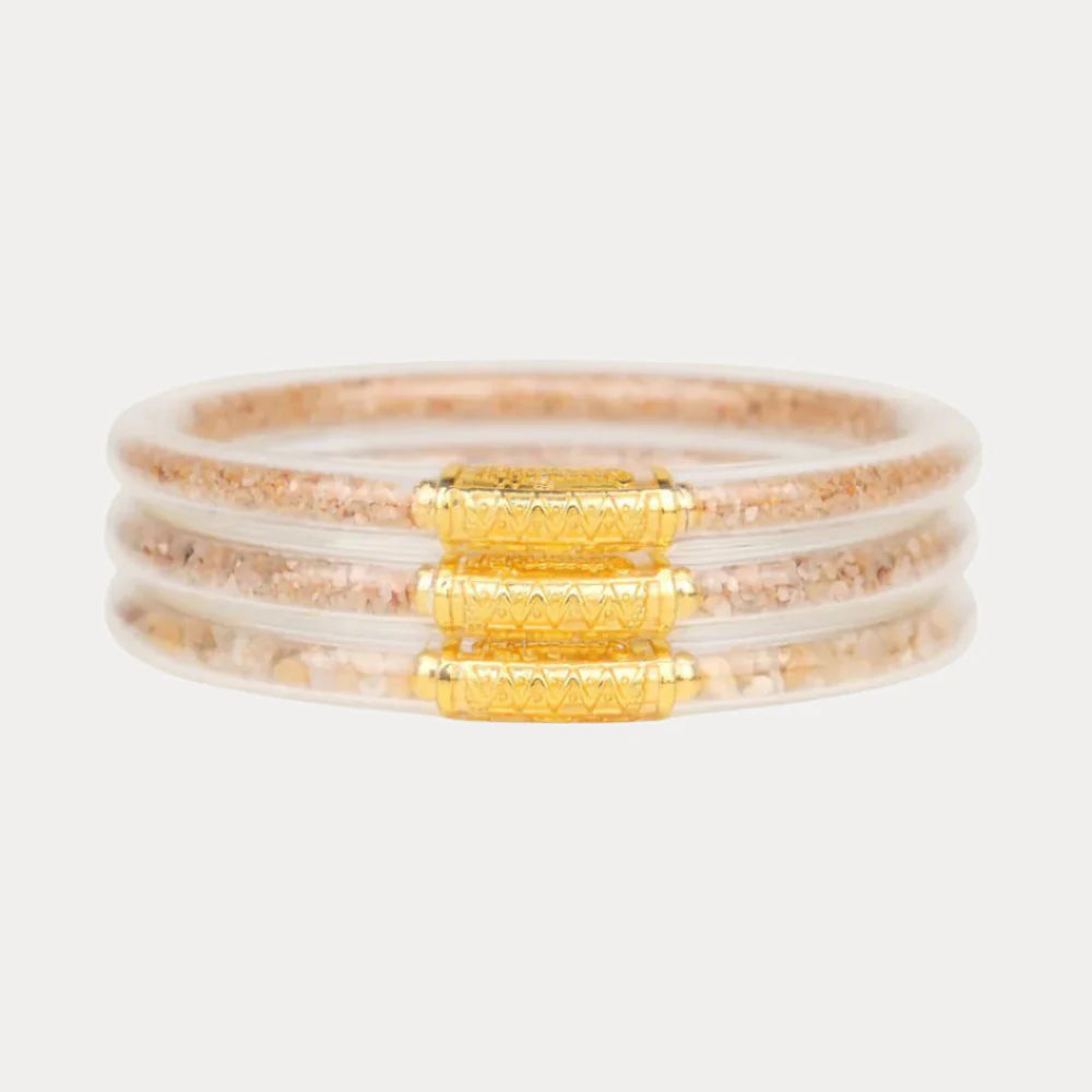 Stack of bracelets with gold and beige accents on a white background