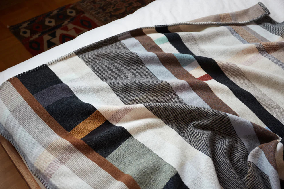 Plaid blanket with brown, beige, and black colors draped over a surface.