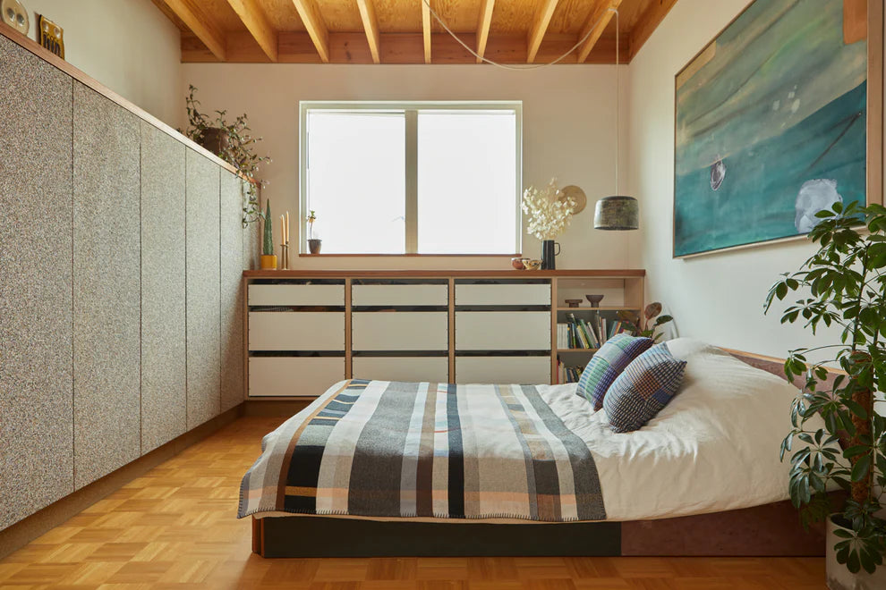 Modern bedroom with wooden floor, bed with striped bedding, and large window.
