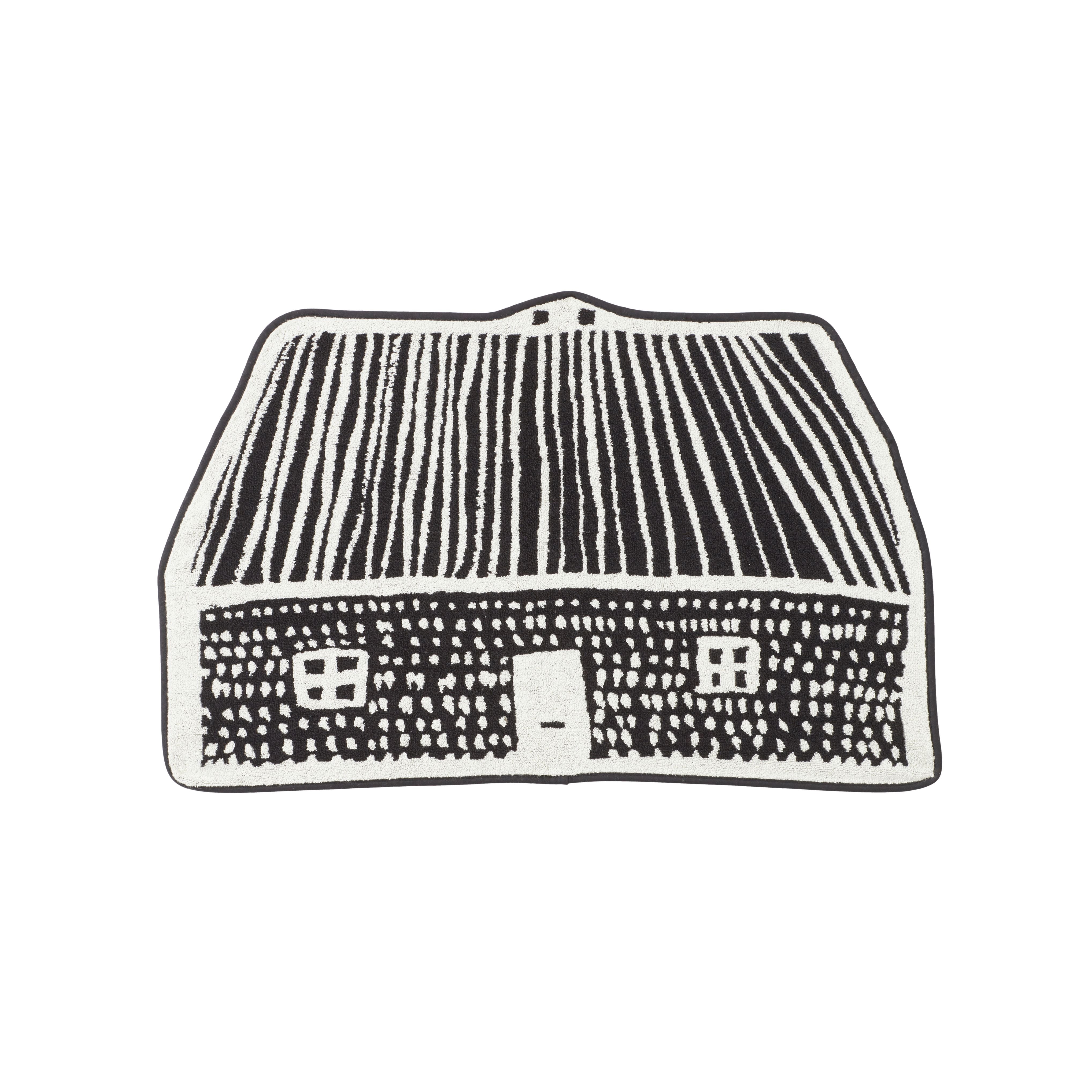 A black and white rug shaped like a house by Donna Wilson, featuring a roof with stripes and a door.