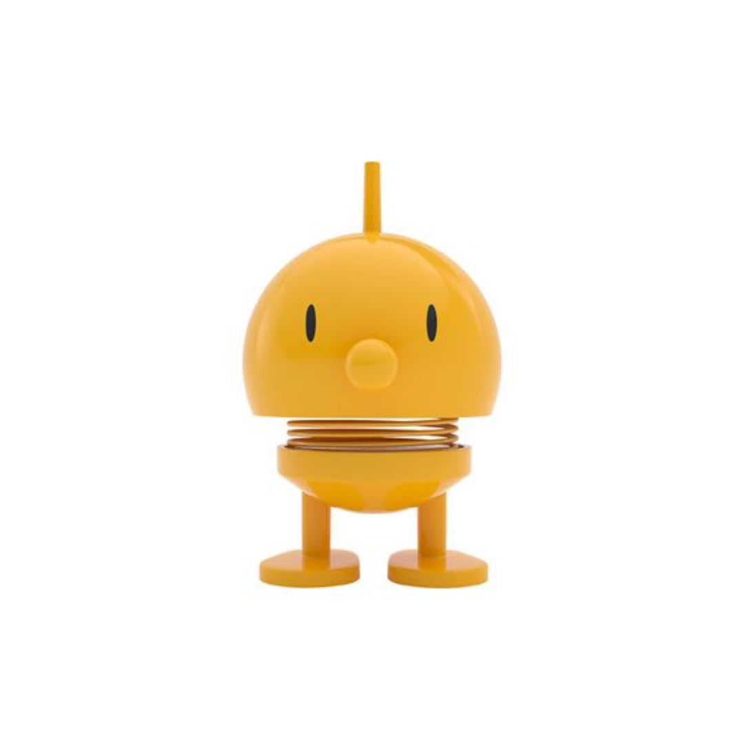 Yellow bobblehead toy with a simple face and spring mechanism.  Short legs and a small antenna on top.