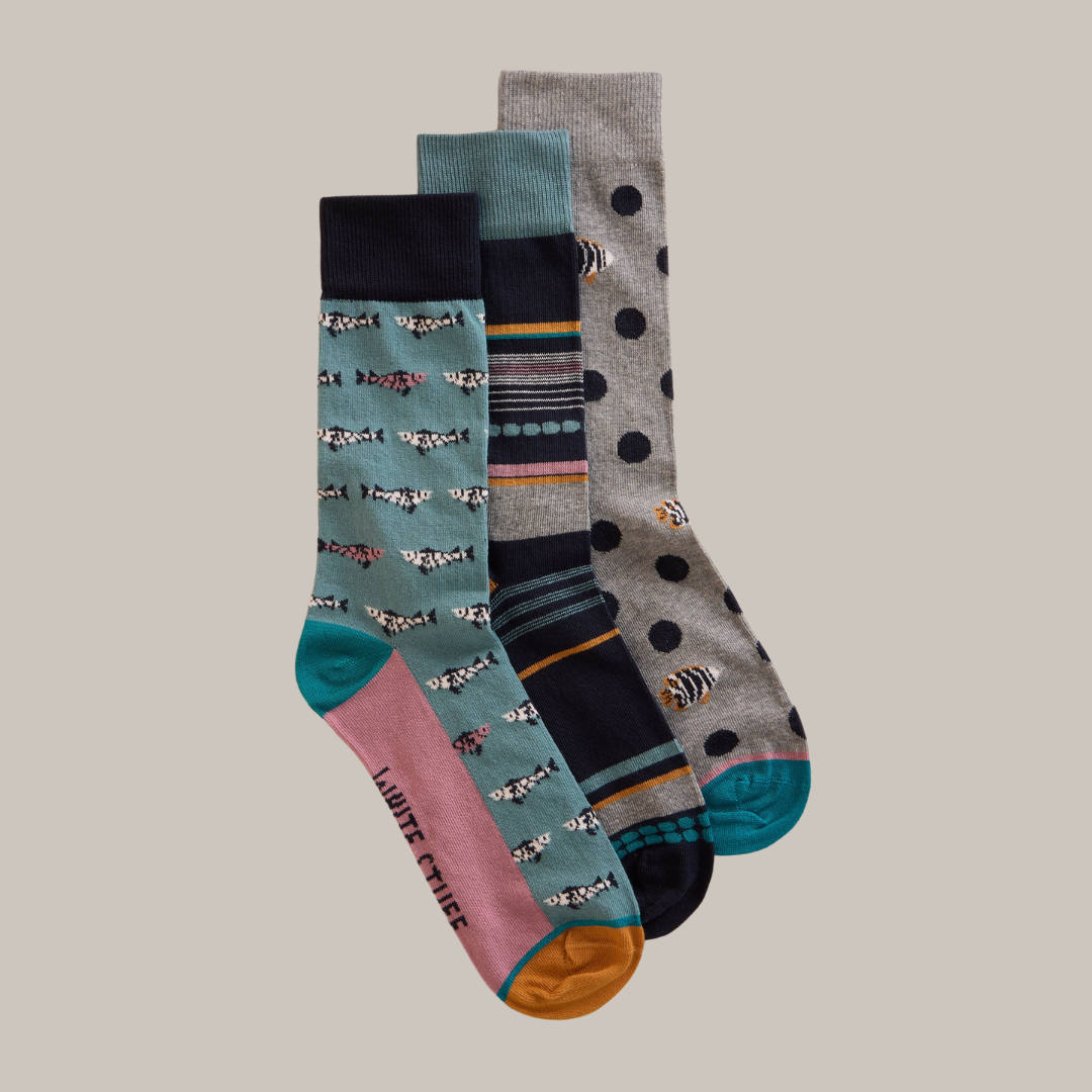 Three pairs of crew socks; one with a teal fish pattern, one with navy and orange stripes, and one with gray polka dots.