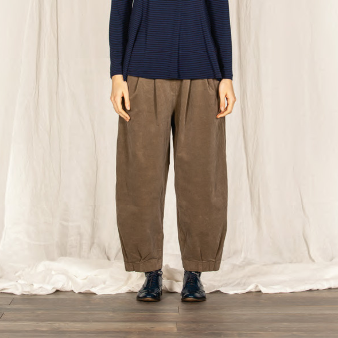 Taupe wide-leg pleated pants with cuffed hems, shown with dark shoes.
