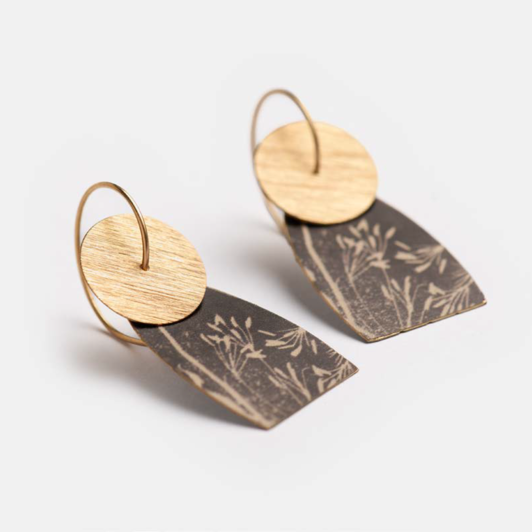 Pair of dangle earrings featuring a wood circle and a dark rectangular pendant with a botanical print.