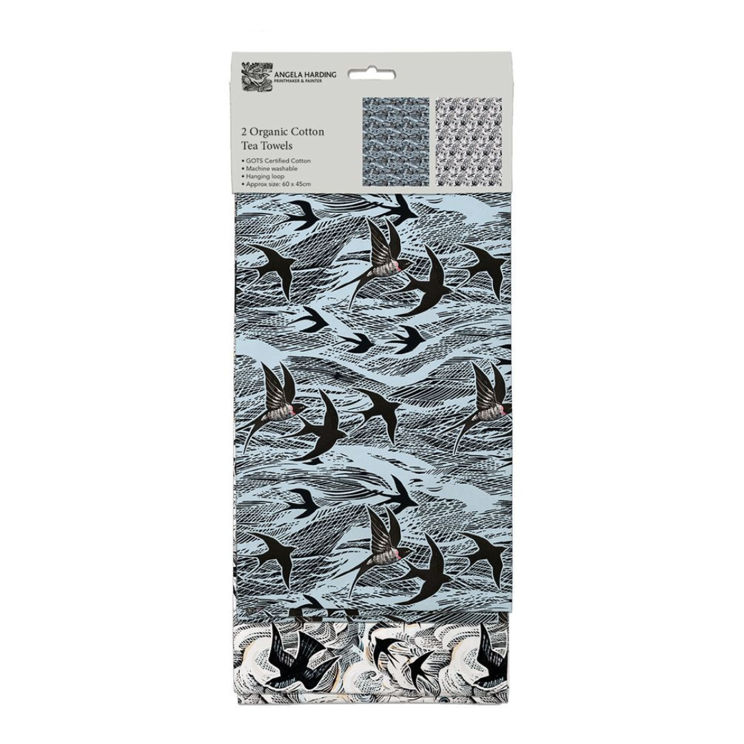 Two GOTS-certified organic cotton tea towels; light blue with a black bird print, and a second design shown on the packaging.
